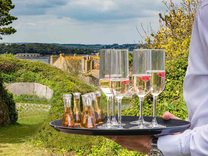 A member of the team is holding a tray of champagne at an event on Drakes Island